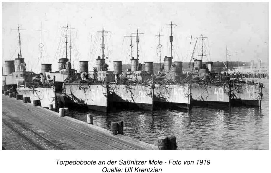 Sechs Torpedoboote liegen mit weiß aufgemalten Kennnummern nebeneinander an der Saßnitzer Mole, im Vordergrund die Holzpoller und Gleise der Kaianlage