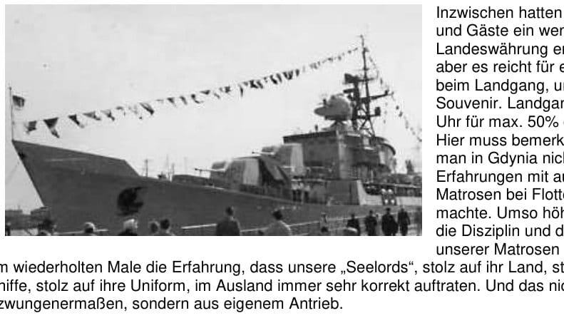 Ein Küstenschutzschiff liegt über die Toppen geflaggt an der Pier, aufgenommen schräg von vorn; auf der Pier stehen Besucher entlang der Absperrung